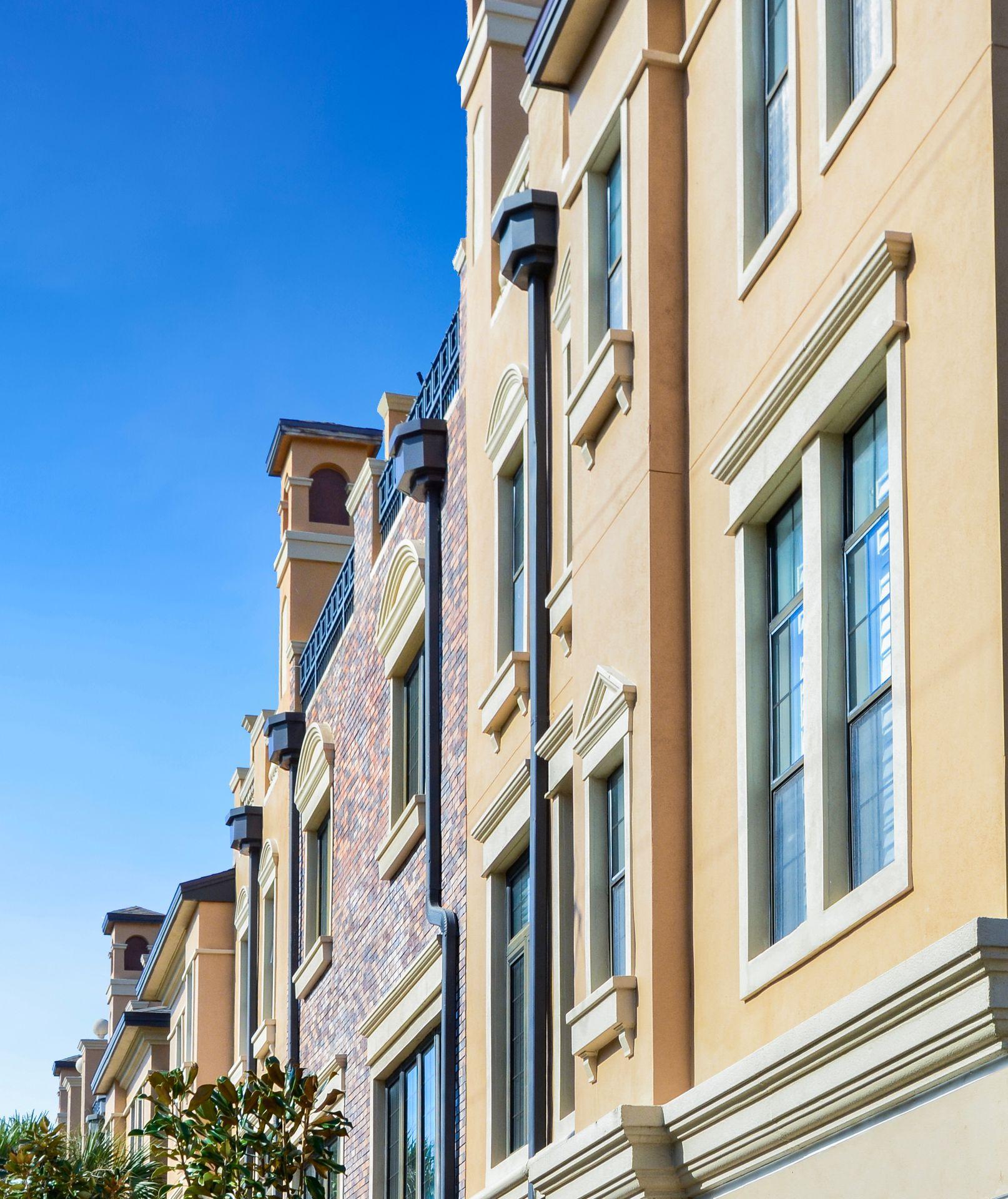 Exterior of stylish multi-story building with decorative windows against a clear blue sky.